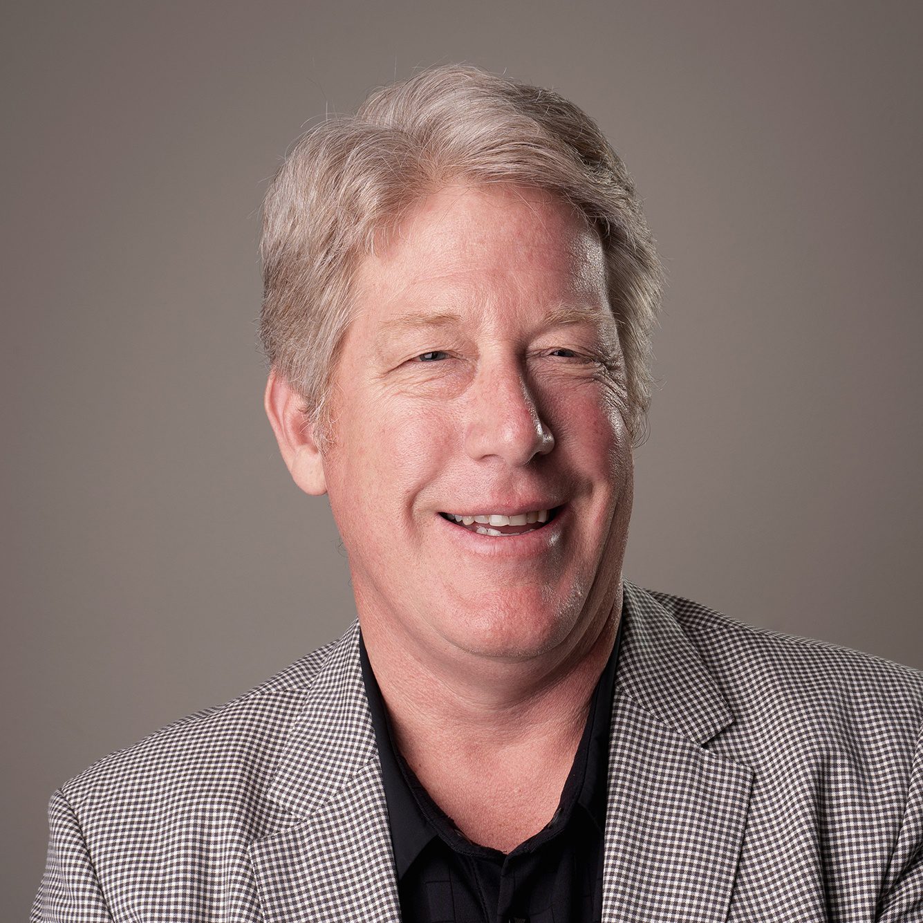 Headshot of financial advisor Syl Michelin in a blue suit with white button up shirt and gray background